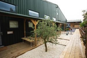 ein großes, grünes Gebäude mit einem Baum davor in der Unterkunft Owen House Farm in Knutsford