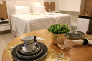 a table with plates and glasses and a bed at Bristol Aline Alagoas in Delmiro Gouveia