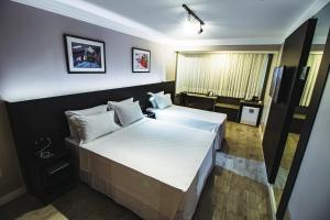 um quarto de hotel com duas camas e uma televisão em Santa Inn Hotel em Balneário Camboriú