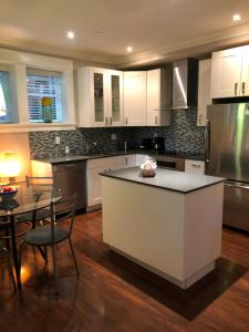 uma cozinha com armários brancos, uma mesa e um balcão em Modern Apartment in Beautiful Kitsilano em Vancouver
