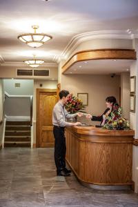 a man and a woman standing at a bar in a lobby at Gullane's Hotel in Ballinasloe