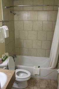 a bathroom with a white tub and a toilet at Travelodge by Wyndham Swift Current in Swift Current