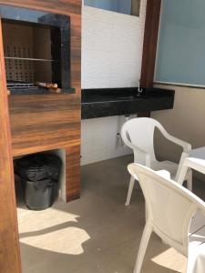 una stanza con due sedie bianche e un tavolo di Bombinhas Residencial Ecomar a Bombinhas