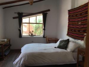 La Chakana Pisac في بيساك: غرفة نوم بسرير ابيض ونافذة