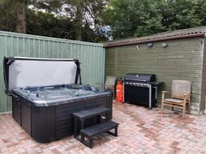 a hot tub and a grill in a backyard at Lletty Ann wynn at Fraithwen Cottages in Newtown