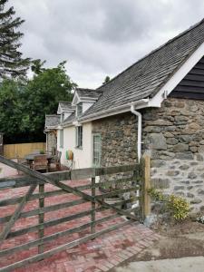 a stone house with a wooden fence in front of it at Lletty Ann wynn at Fraithwen Cottages in Newtown