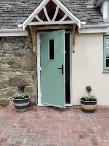 een voordeur van een huis met twee potplanten bij Lletty Ann wynn at Fraithwen Cottages in Newtown