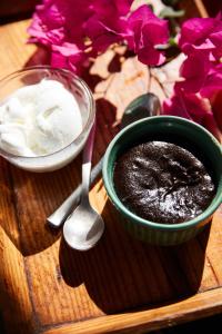 a bowl of chocolate pudding next to a spoon and flowers at Jamboree Creek Yoga in Mandrem
