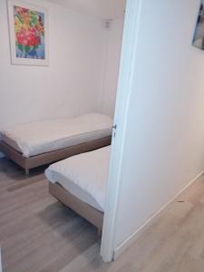Habitación con 2 camas, paredes blancas y suelo de madera. en Apartment StayWell Amsterdam Free Parking, en Ámsterdam