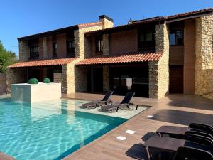 a house with a swimming pool with chairs in front of it at 2 Apartamentos en villa con piscina privada en Asturias El Marquesau in Noriega