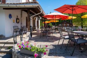 a patio with tables and chairs with umbrellas and flowers at Auberge du Prévoux in Le Locle