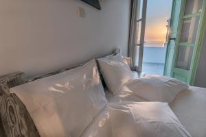 a bed with white pillows sitting next to a window at The Cliff Reflections - Adults Only in Megalokhori