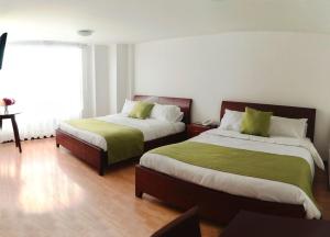 1 dormitorio con 2 camas con sábanas verdes y ventana en Nogal Suite Hotel, en Pasto