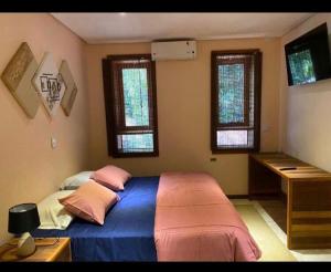 a bedroom with a bed with pink and blue sheets and windows at Espaço Tajj in São Roque