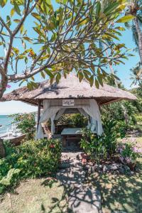 a picnic shelter on the beach with a tree at Santai Hotel in Amed