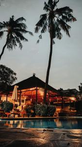 a resort with a palm tree and a swimming pool at Santai Hotel in Amed
