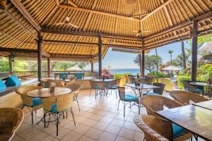 a restaurant with tables and chairs and a view of the ocean at Santai Hotel in Amed