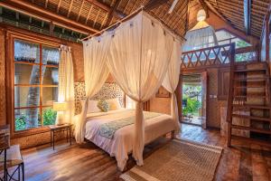 a bedroom with a bed with a canopy at Santai Hotel in Amed