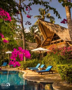 a resort with a pool and chairs and pink flowers at Santai Hotel in Amed