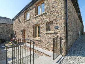 a stone building with a gate in front of it at Grange Cottage in Crediton