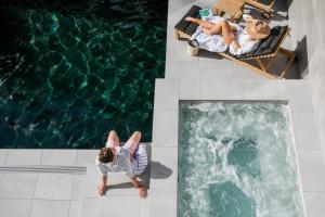 a woman laying on a bed next to a swimming pool at On The Beach Noosa Resort in Noosa Heads
