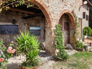 een bakstenen gebouw met een boog en enkele planten bij Belvilla by OYO Flat in farmhouse with pool in Pian di Scò