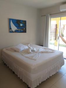 - un lit blanc dans une chambre avec fenêtre dans l'établissement Casa Temporada Suítes, à Maragogi