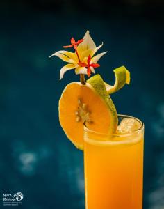 a glass of orange juice with a flower on top at Santai Hotel in Amed