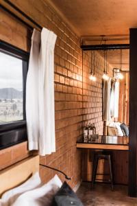 Cette chambre dispose d'un mur en briques, d'une table et d'une fenêtre. dans l'établissement Santulan, à Valle de Guadalupe