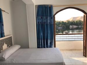 a bedroom with a bed and a large window at NOBATiA Guest House in Aswan