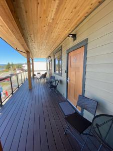 een houten terras met stoelen en een deur op een huis bij Beyond Bliss Suites & Spa in Powell River