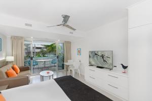 
a living room filled with furniture and a tv at By The Sea Port Douglas in Port Douglas
