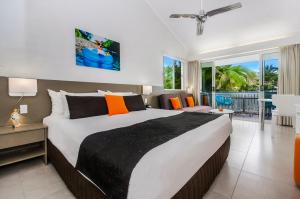 
a hotel room with a large bed and a large window at By The Sea Port Douglas in Port Douglas
