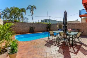 un patio con mesa y sillas junto a una piscina en Matilda Motel en Bundaberg