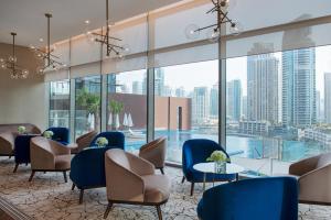 un vestíbulo con sillas, mesas y una piscina en Jumeirah Living Marina Gate Dubai en Dubái