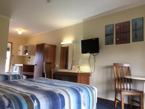 a hotel room with a bed and a tv on the wall at The Finley Palm Motor Inn in Finley