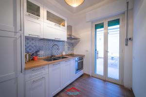 una cucina con mobili bianchi e un lavello di Casa stellata Napoli home in the center a Napoli