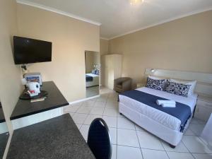 a bedroom with a bed and a desk and a tv at Singatha Guesthouse in Durban
