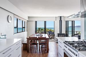 a kitchen with a table and chairs and a view of the ocean at The Big Bach in Wellington