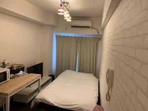 Kleines Zimmer mit einem Bett und einem Schreibtisch mit einem Computer. in der Unterkunft Exsaison Shirokita 705 in Osaka