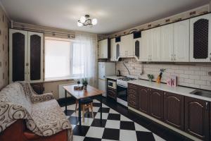 een keuken met witte kasten en een zwart-wit geruite vloer bij Apartment on Kharkovskaya 2 floor in Sumy