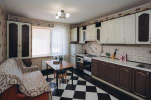 a kitchen with white cabinets and a black and white checkered floor at Apartment on Kharkovskaya 2 floor in Sumy