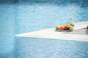 einen Obstteller und ein Glas Wein neben einem Pool in der Unterkunft Splendour Resort in Firostefani