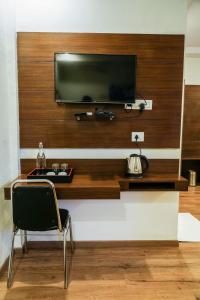 a television on a wall with a chair in a room at Suraksha Stay ITPL Hotel Banglore in Bengaluru