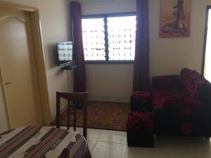 - un salon avec un canapé, une chaise et une fenêtre dans l'établissement Résidence Comara, à Marcory