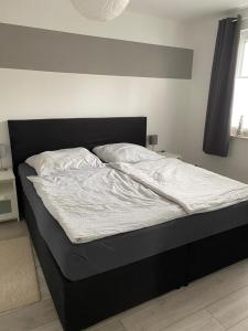 a bed with white sheets and pillows in a bedroom at Schöne 54qm Fewo nahe Rostock und Warnemünde in Lambrechtshagen