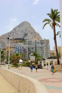 people walking on the beach with a mountain in the background at Mesana 102 / Penthouse in Calpe