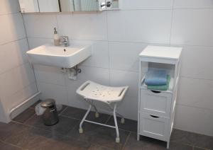 a white bathroom with a sink and a stool at Schönberg - Schuster Raths Kate in Schönberg in Holstein