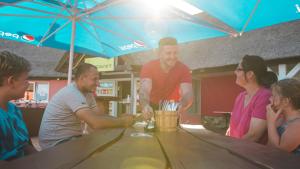 a group of people sitting around a table at a bar at Eurocamp Spreewaldtor in Groß Leuthen