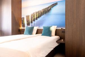 two beds in a room with a painting of a pier at Hotel Nelson in Knokke-Heist